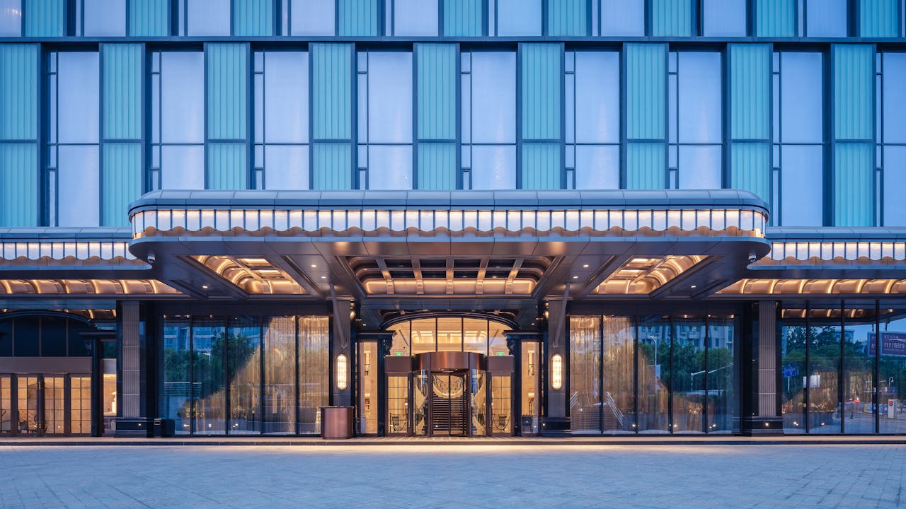 Elegant modern hotel entrance with glass facade and ambient lighting.